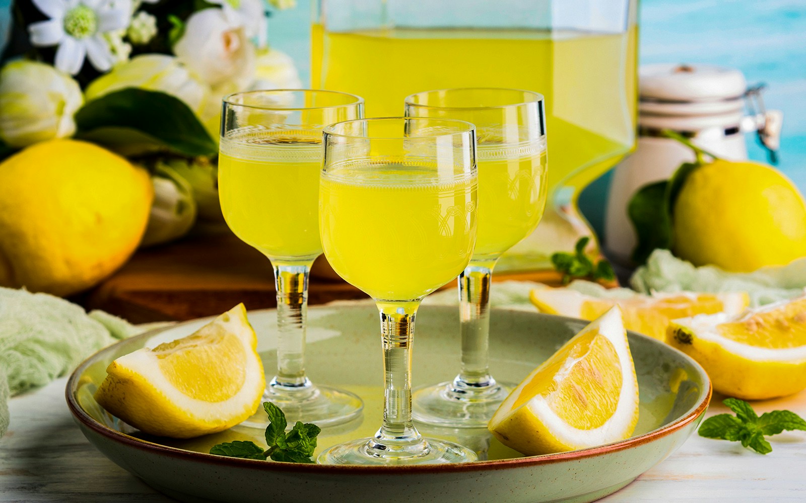 Glasses of limoncello with fresh lemon slices and mint leaves.