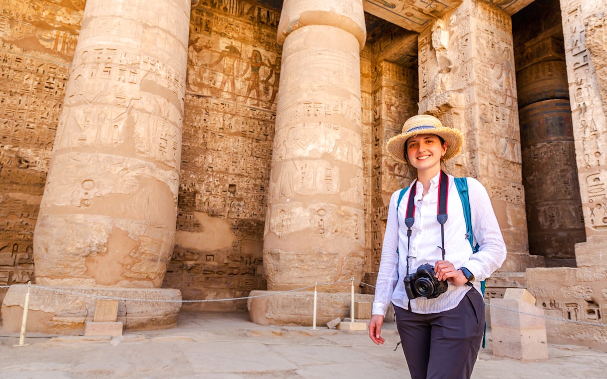 Tourist exploring Karnak Temple with hieroglyphics on columns, Luxor, Egypt.