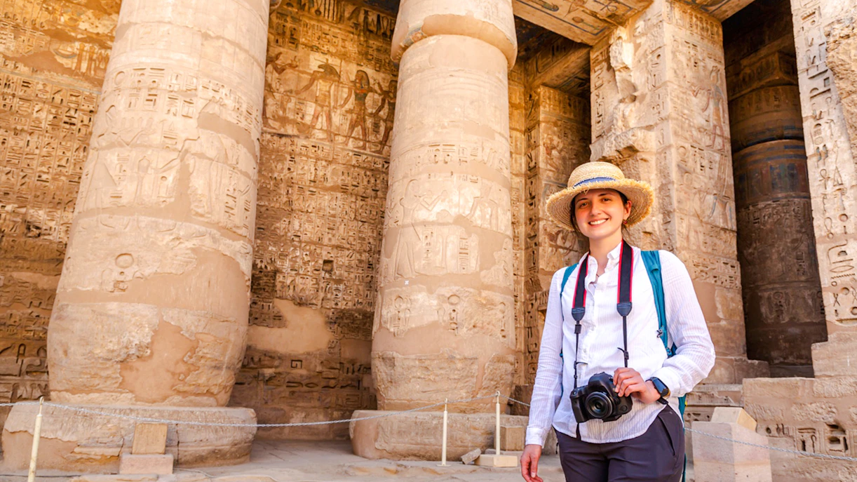 Tourist exploring Karnak Temple with hieroglyphics on columns, Luxor, Egypt.