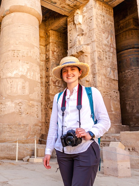 Tourist exploring Karnak Temple with hieroglyphics on columns, Luxor, Egypt.
