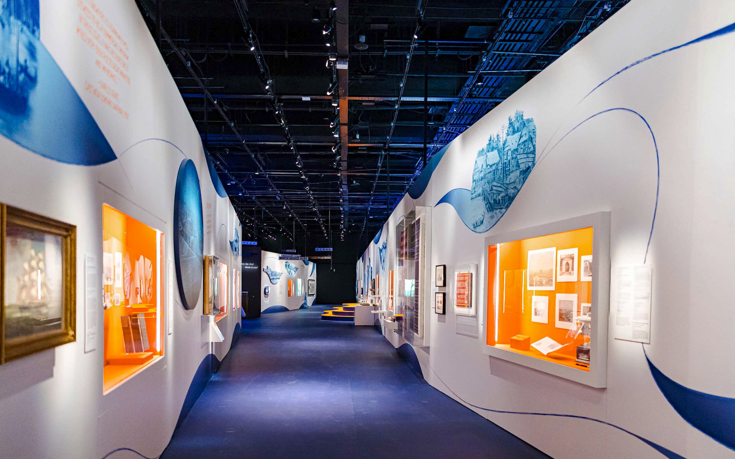 Walkway through exhibition at the National Museum of Singapore with illuminated displays.