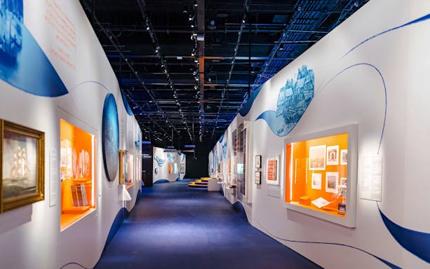 Walkway through exhibition at the National Museum of Singapore with illuminated displays.