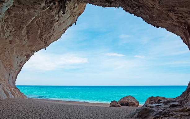 Cave opening view of Cala Luna beach with turquoise sea in Sardinia.