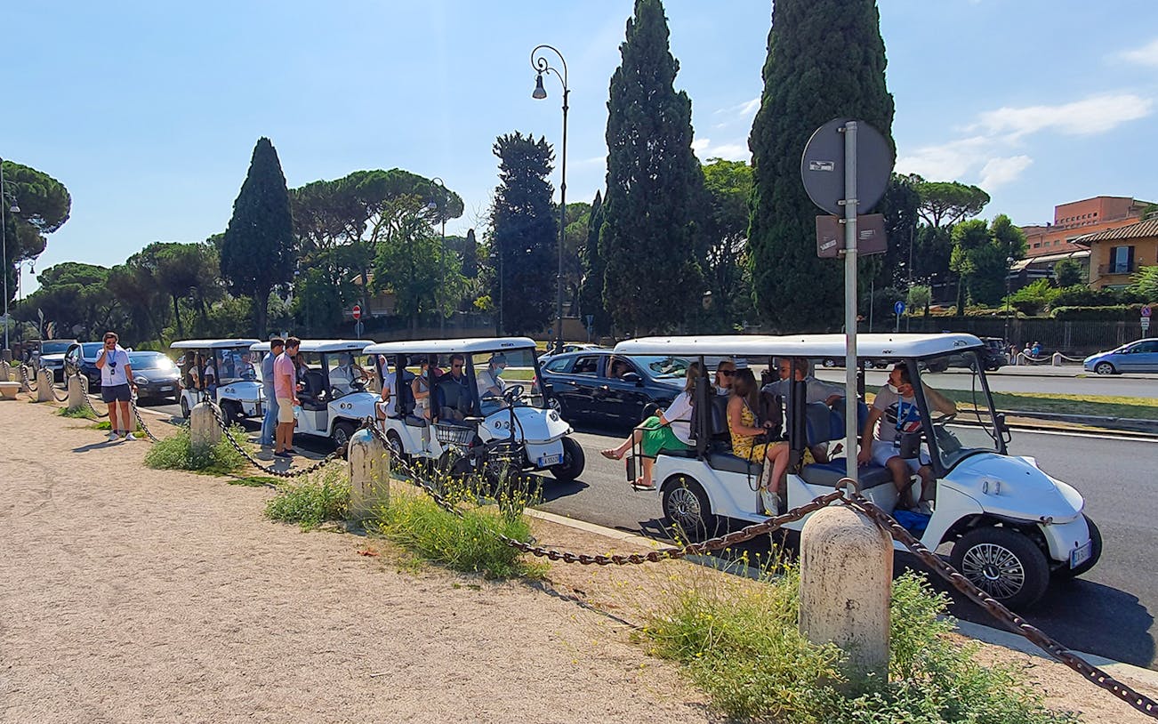 Tourists exploring Rome landmarks on a golf cart tour.