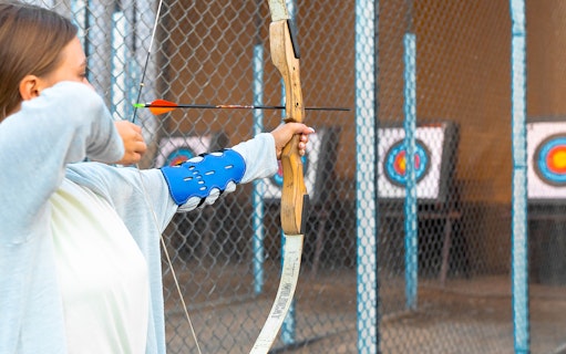 Person practicing archery at Hatta Wadi Hub with targets in the background.