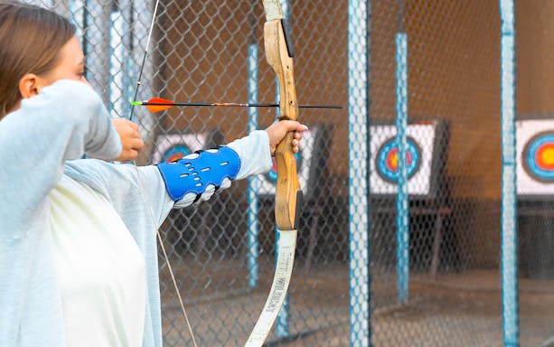 Person practicing archery at Hatta Wadi Hub with targets in the background.