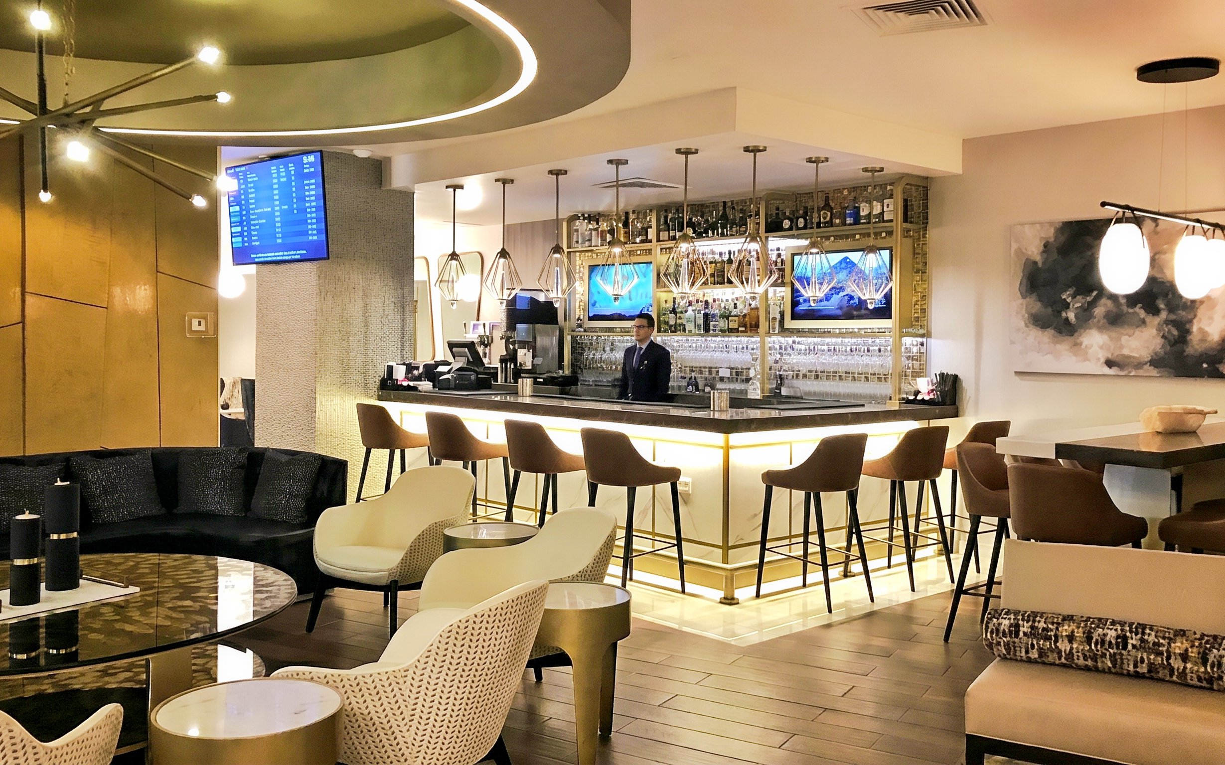 Bar counter at MERA Business Lounge, Cancun Airport, with seating and modern decor.