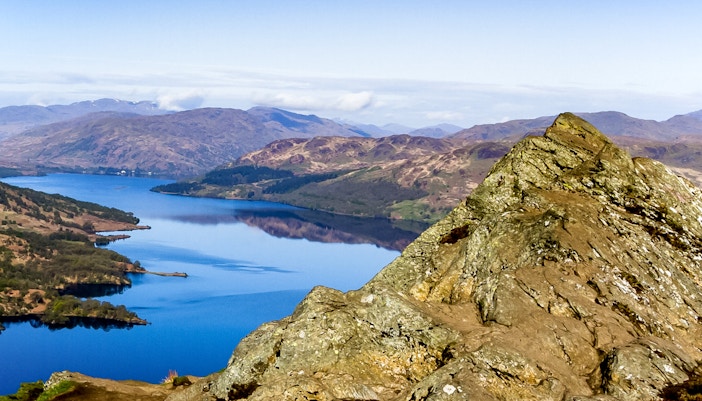 Loch Lomond view with rocky foreground and distant hills, Scotland.