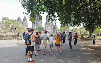 Tour group exploring Prambanan Temple complex in Yogyakarta, Indonesia.