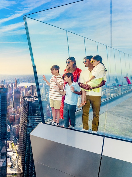Family enjoying view from NYC observation deck with skyline and Empire State Building.