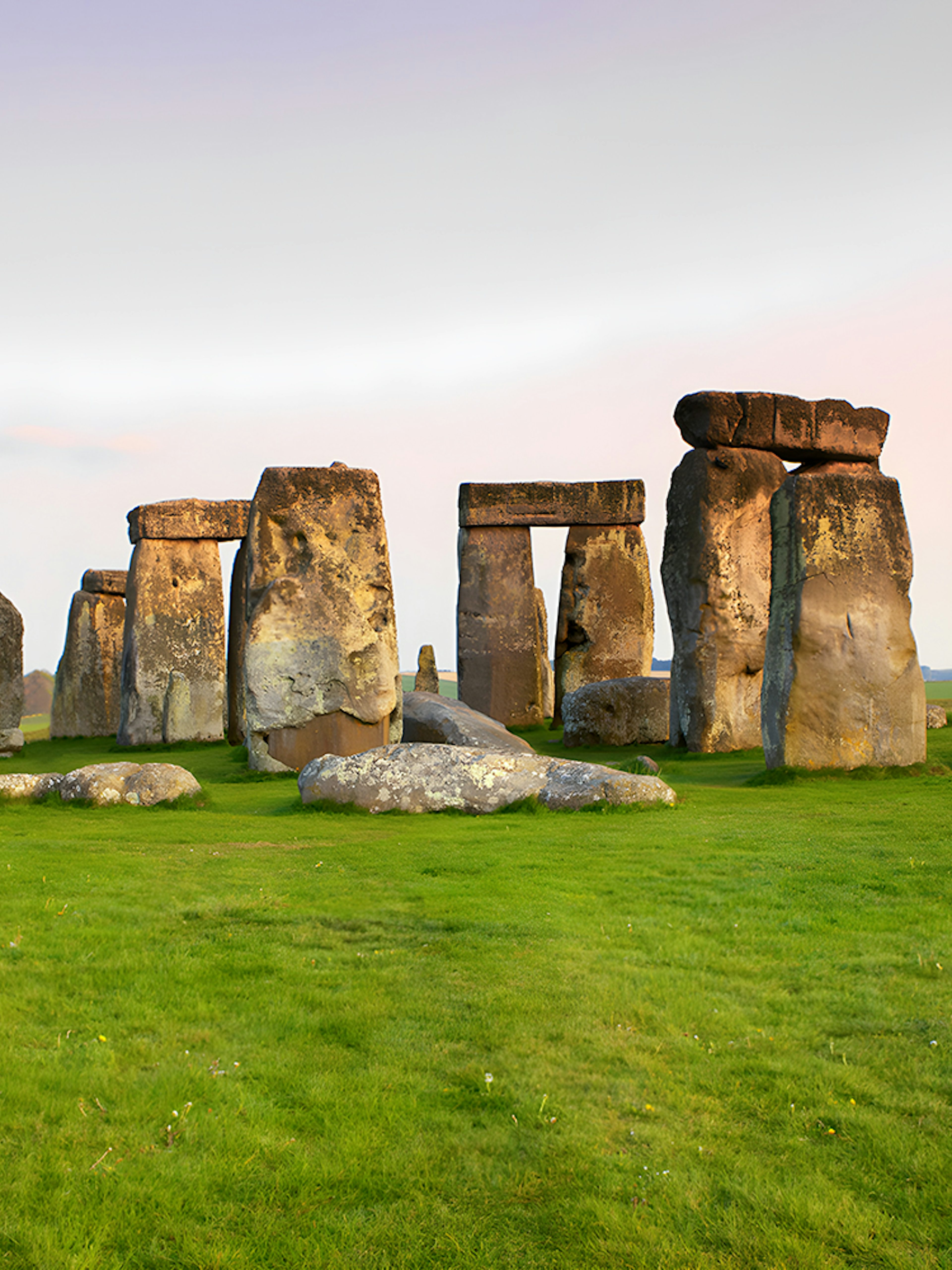 Stonehenge stone circle on a grassy field at sunset, Wiltshire, England.