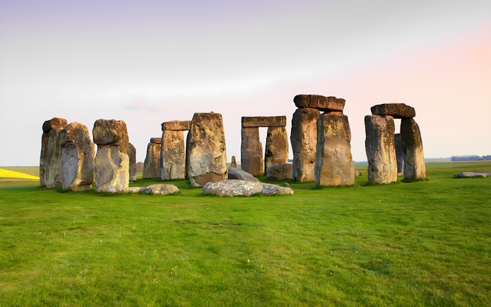 Stonehenge stone circle on a grassy field at sunset, Wiltshire, England.