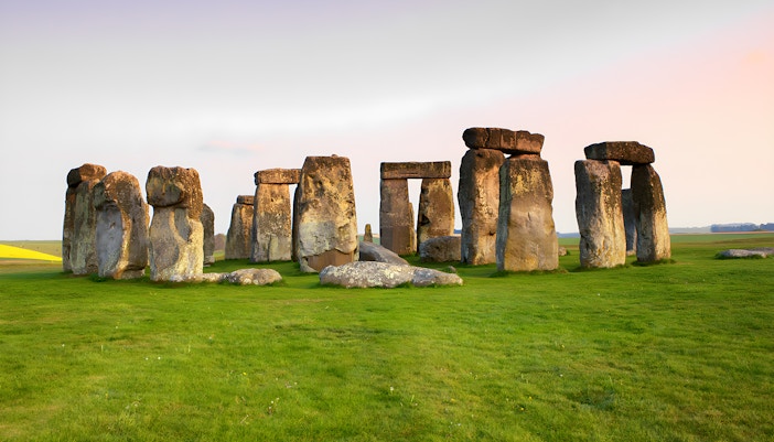 Stonehenge stone circle on a grassy field at sunset, Wiltshire, England.