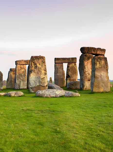 Stonehenge stone circle on a grassy field at sunset, Wiltshire, England.