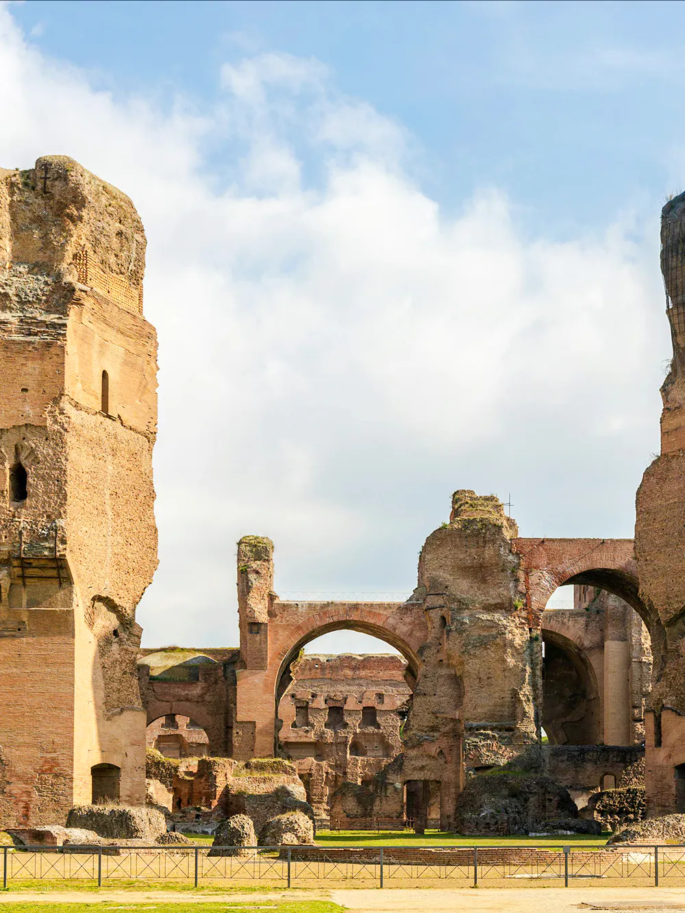 Ruins of the Baths of Caracalla in Rome's historic center, showcasing ancient arches and stone structures.