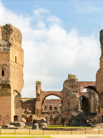 Ruins of the Baths of Caracalla in Rome's historic center, showcasing ancient arches and stone structures.