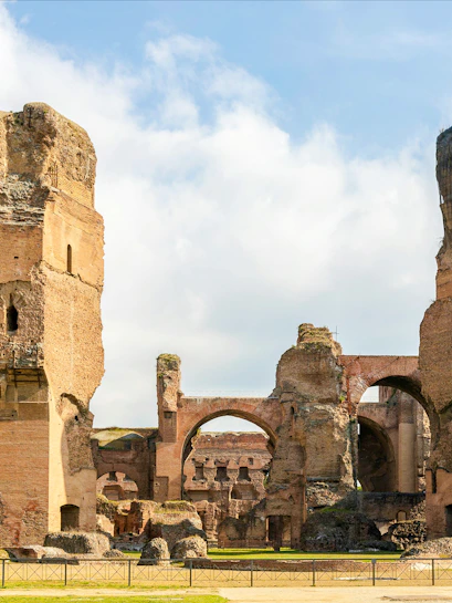 Ruins of the Baths of Caracalla in Rome's historic center, showcasing ancient arches and stone structures.