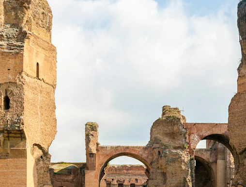 Ruins of the Baths of Caracalla in Rome's historic center, showcasing ancient arches and stone structures.