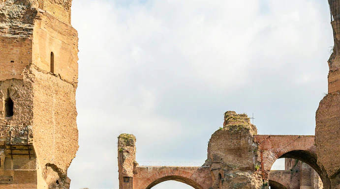 Ruins of the Baths of Caracalla in Rome's historic center, showcasing ancient arches and stone structures.