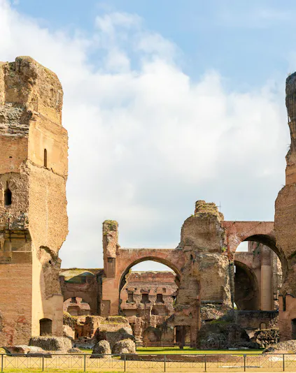 Ruins of the Baths of Caracalla in Rome's historic center, showcasing ancient arches and stone structures.