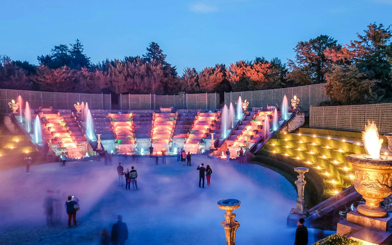 Versailles gardens illuminated during night fountains show with visitors, Paris.