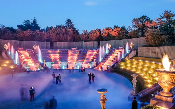 Versailles gardens illuminated during night fountains show with visitors, Paris.
