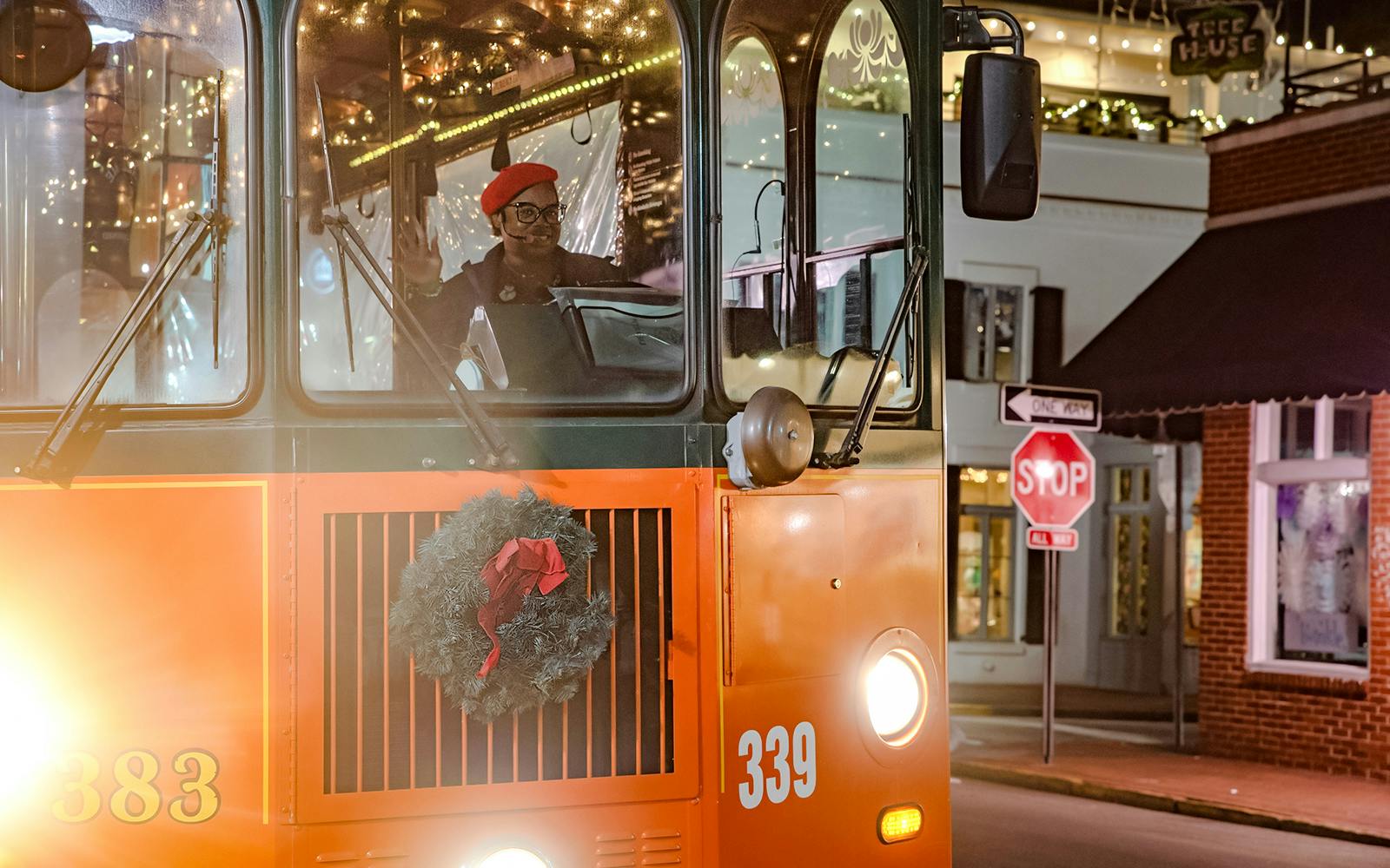 Old Town Trolley decorated with holiday lights and wreath in Savannah at night.