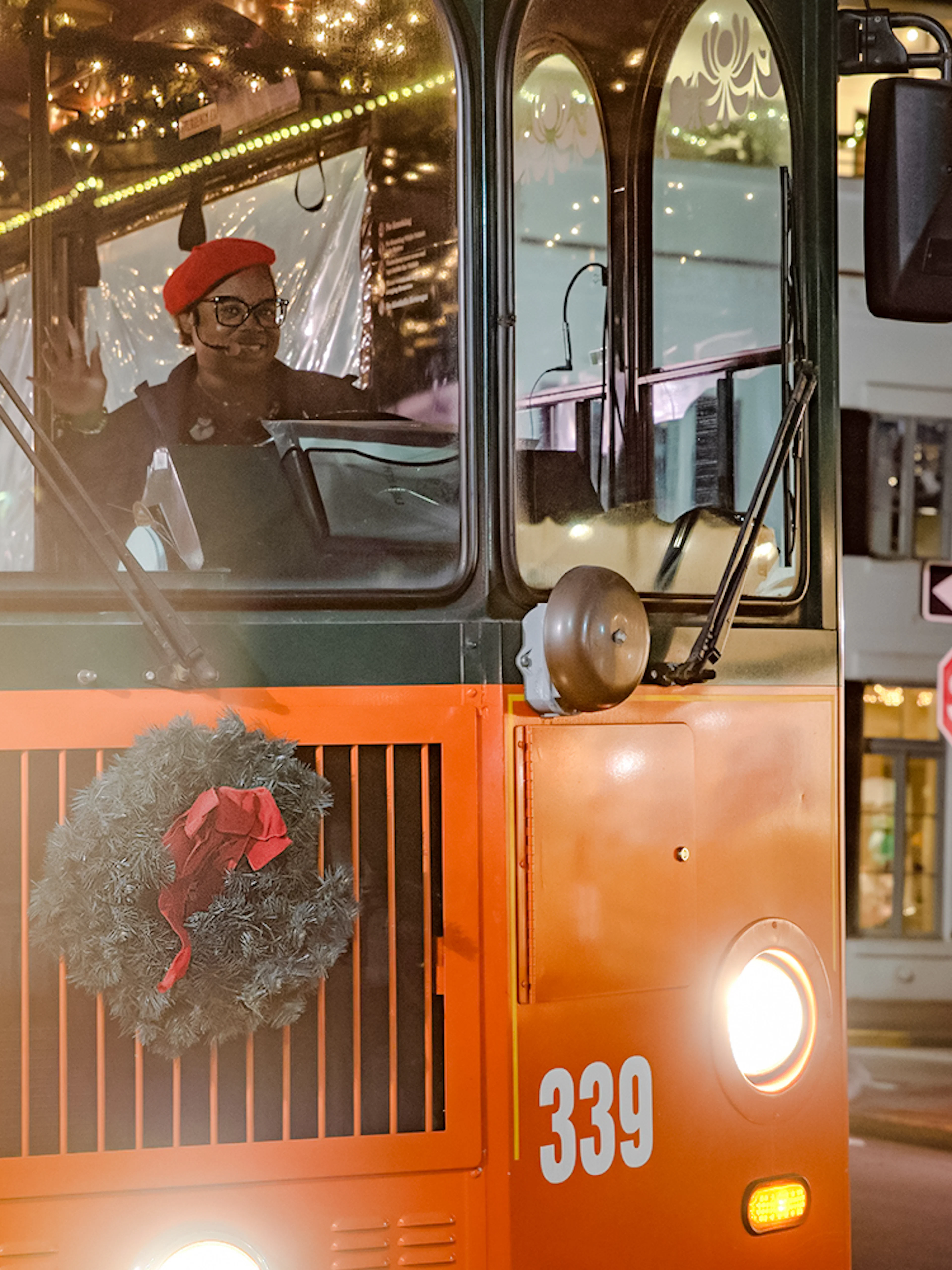 Old Town Trolley decorated with holiday lights and wreath in Savannah at night.