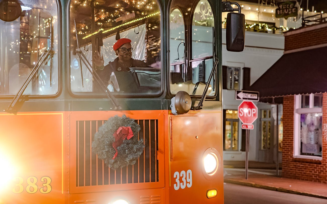 Old Town Trolley decorated with holiday lights and wreath in Savannah at night.
