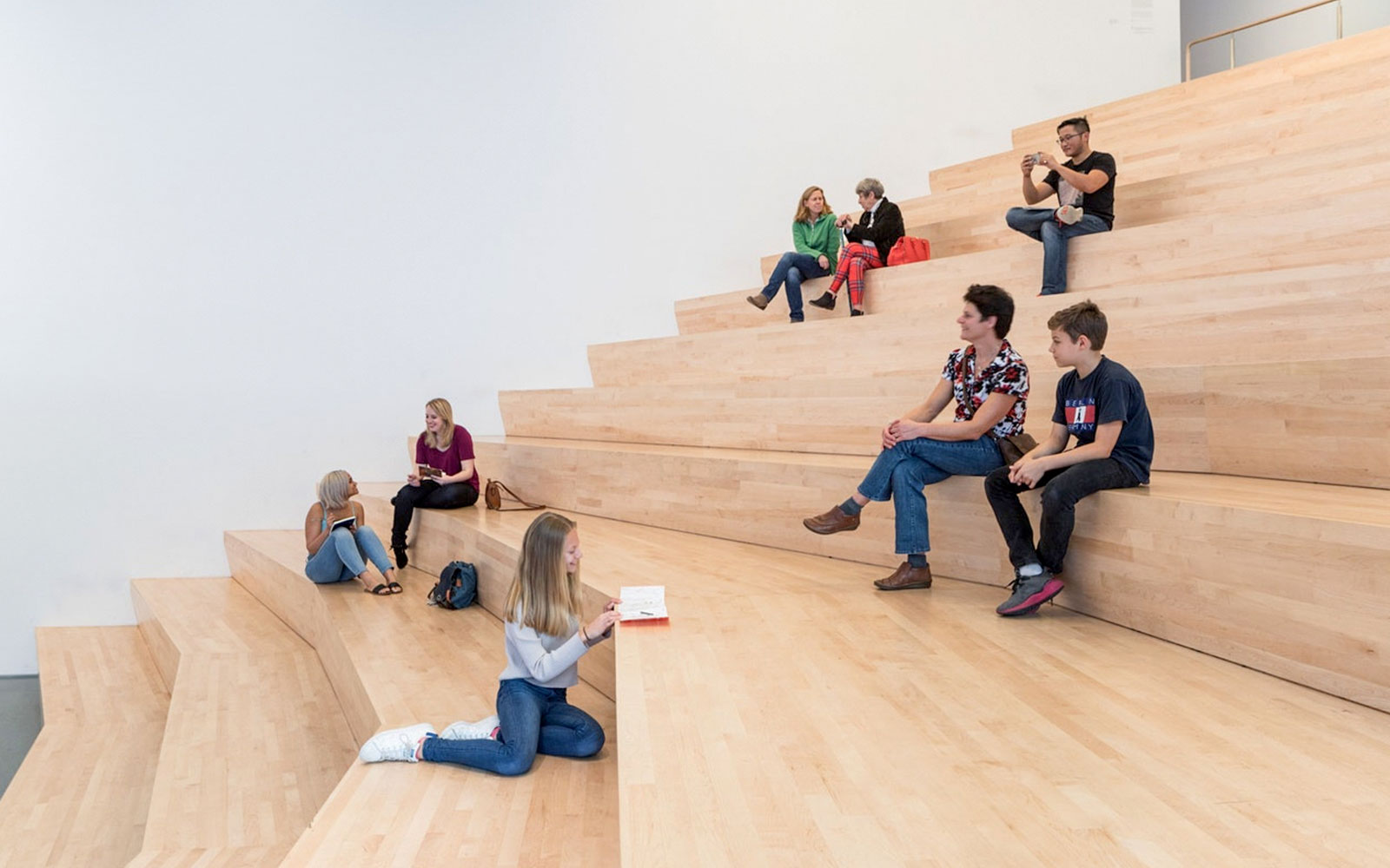 Visitors sitting on wooden steps inside San Francisco Museum of Modern Art.