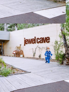 Jewel Cave entrance in Margaret River, featuring a cave explorer cutout and surrounding greenery.
