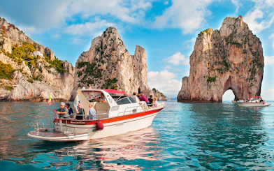 Boat tour near Faraglioni rock formations, Capri, Italy.