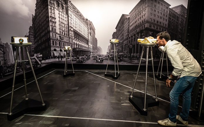 Man viewing cityscape through binoculars on 86th floor, VIP Sunrise Experience.