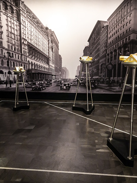 Man viewing cityscape through binoculars on 86th floor, VIP Sunrise Experience.