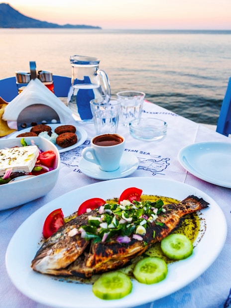 Grilled fish and Greek salad on a seaside table in Santorini.