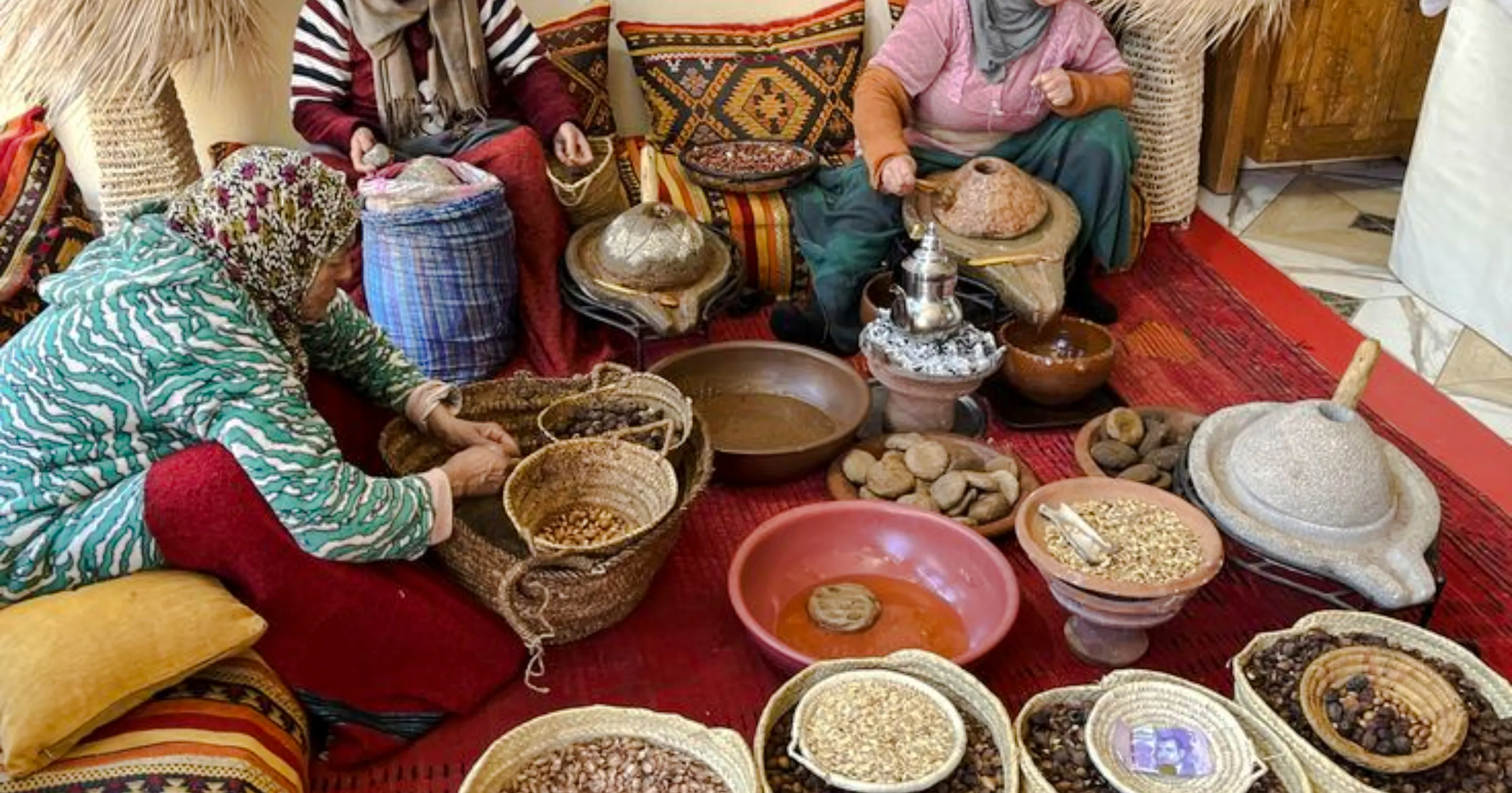 Women processing argan nuts with traditional tools in Essaouira countryside.