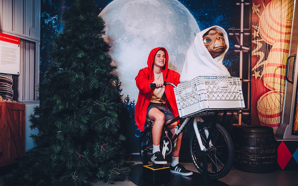 Visitor posing with E.T. on a bicycle at Madame Tussauds Sydney.