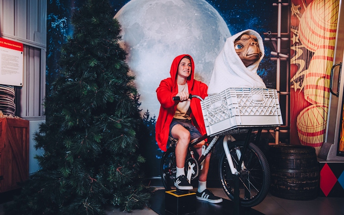 Visitor posing with E.T. on a bicycle at Madame Tussauds Sydney.