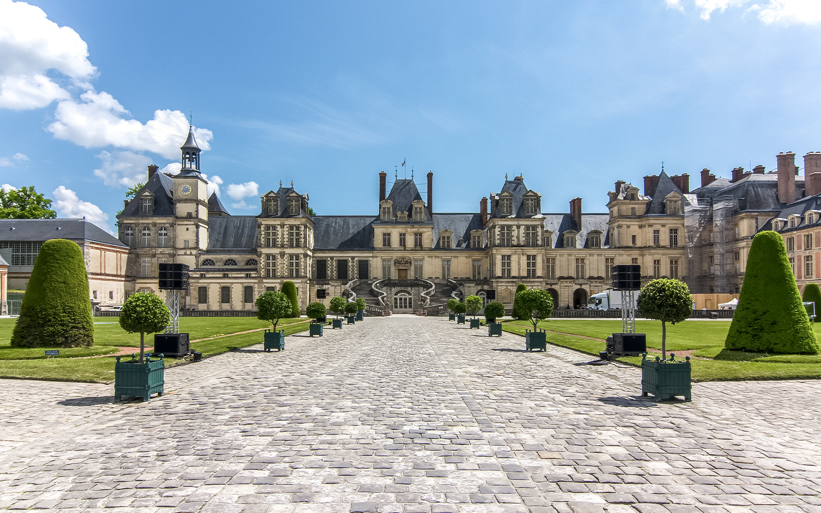Chateau de Fontainebleau courtyard with manicured gardens and historic architecture.
