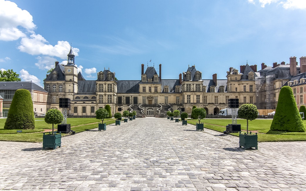 Chateau de Fontainebleau courtyard with manicured gardens and historic architecture.