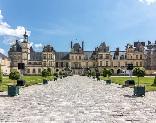 Chateau de Fontainebleau courtyard with manicured gardens and historic architecture.