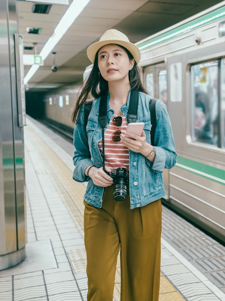 Young woman using smartphone at Osaka tube station, Japan.