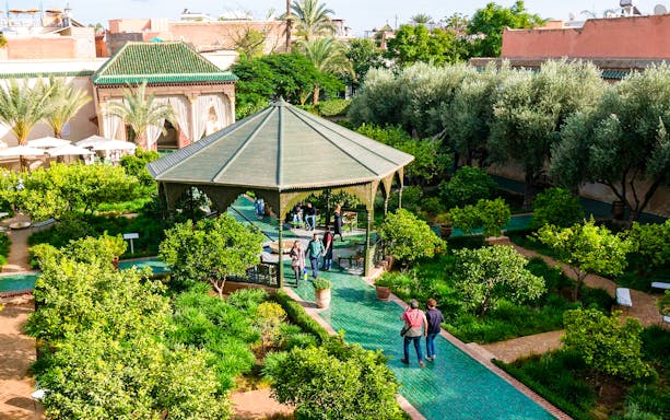 Jardin Secret garden with gazebo and visitors in Marrakech, Morocco.