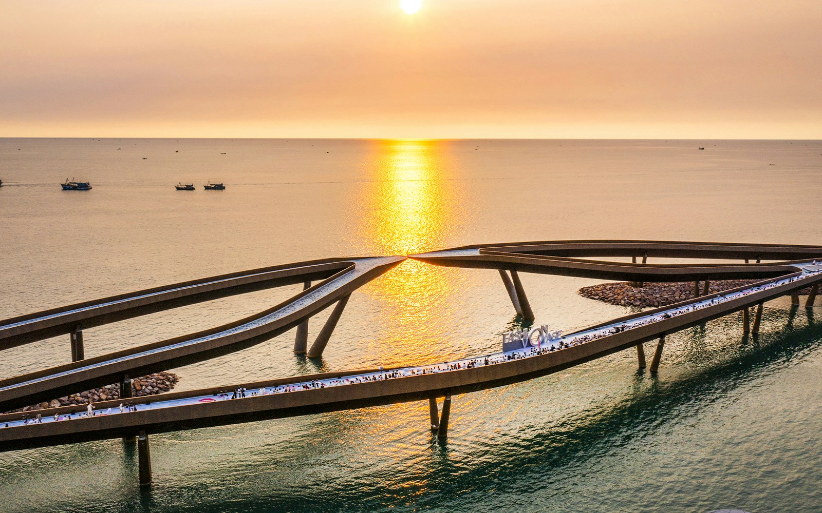 Kiss Bridge at sunset in Hon Thom, Phu Quoc, with people walking along the structure.