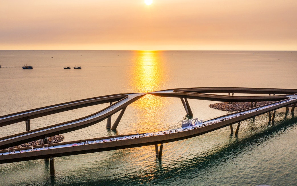 Kiss Bridge at sunset in Hon Thom, Phu Quoc, with people walking along the structure.