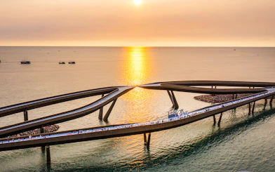 Kiss Bridge at sunset in Hon Thom, Phu Quoc, with people walking along the structure.