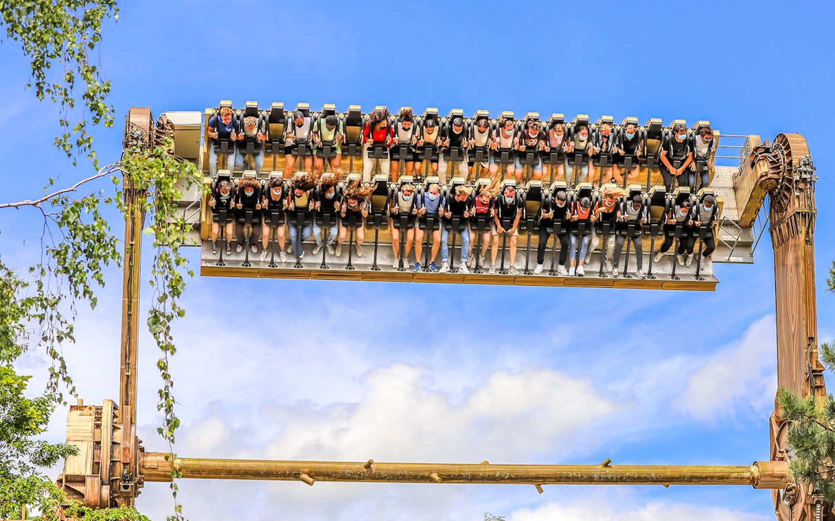 Visitors on a thrill ride at Walibi Belgium in Wavre, suspended upside down against a blue sky.