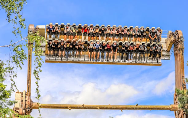 Visitors on a thrill ride at Walibi Belgium in Wavre, suspended upside down against a blue sky.