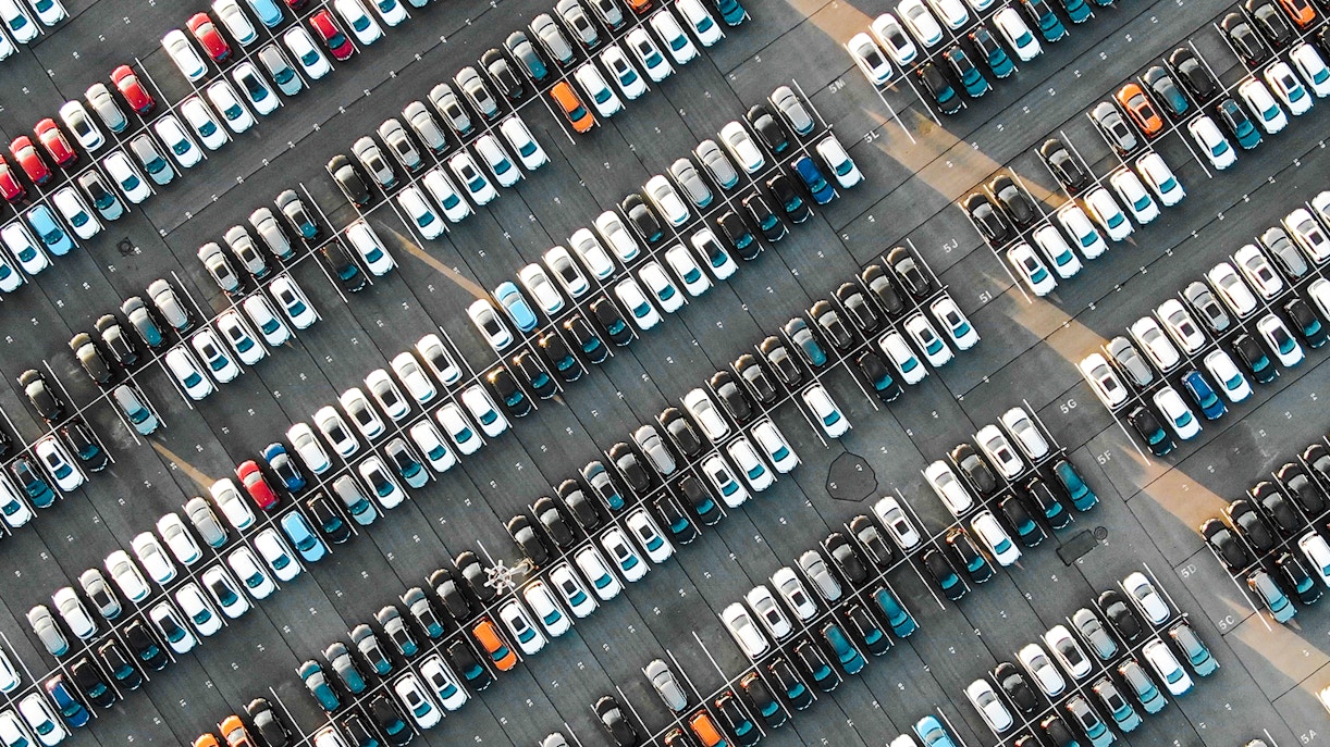 Aerial view of a filled parking lot with rows of parked cars.