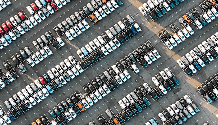 Aerial view of a filled parking lot with rows of parked cars.